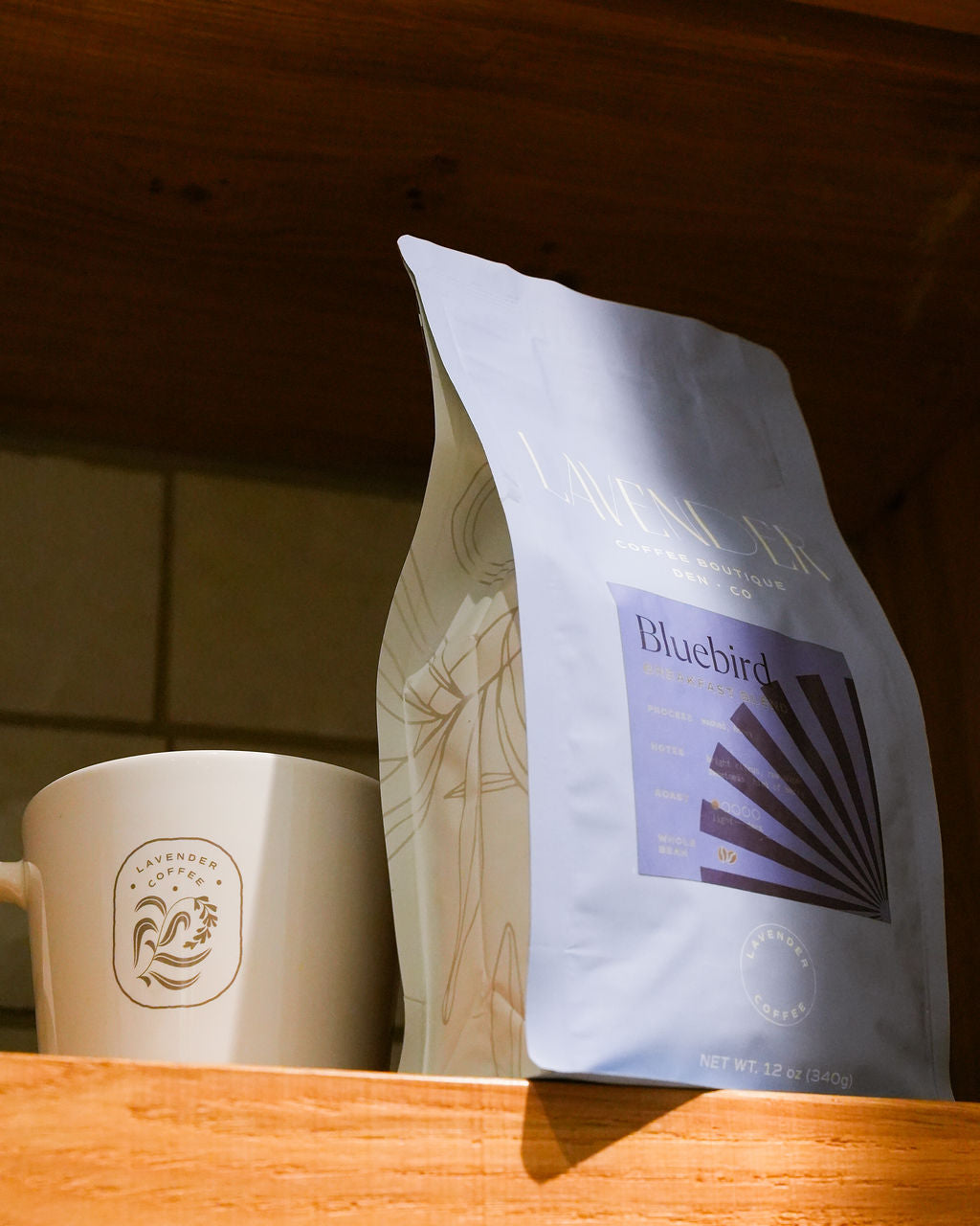 Bluebird Breakfast Blend light roast coffee bag on wooden table with ceramic mug