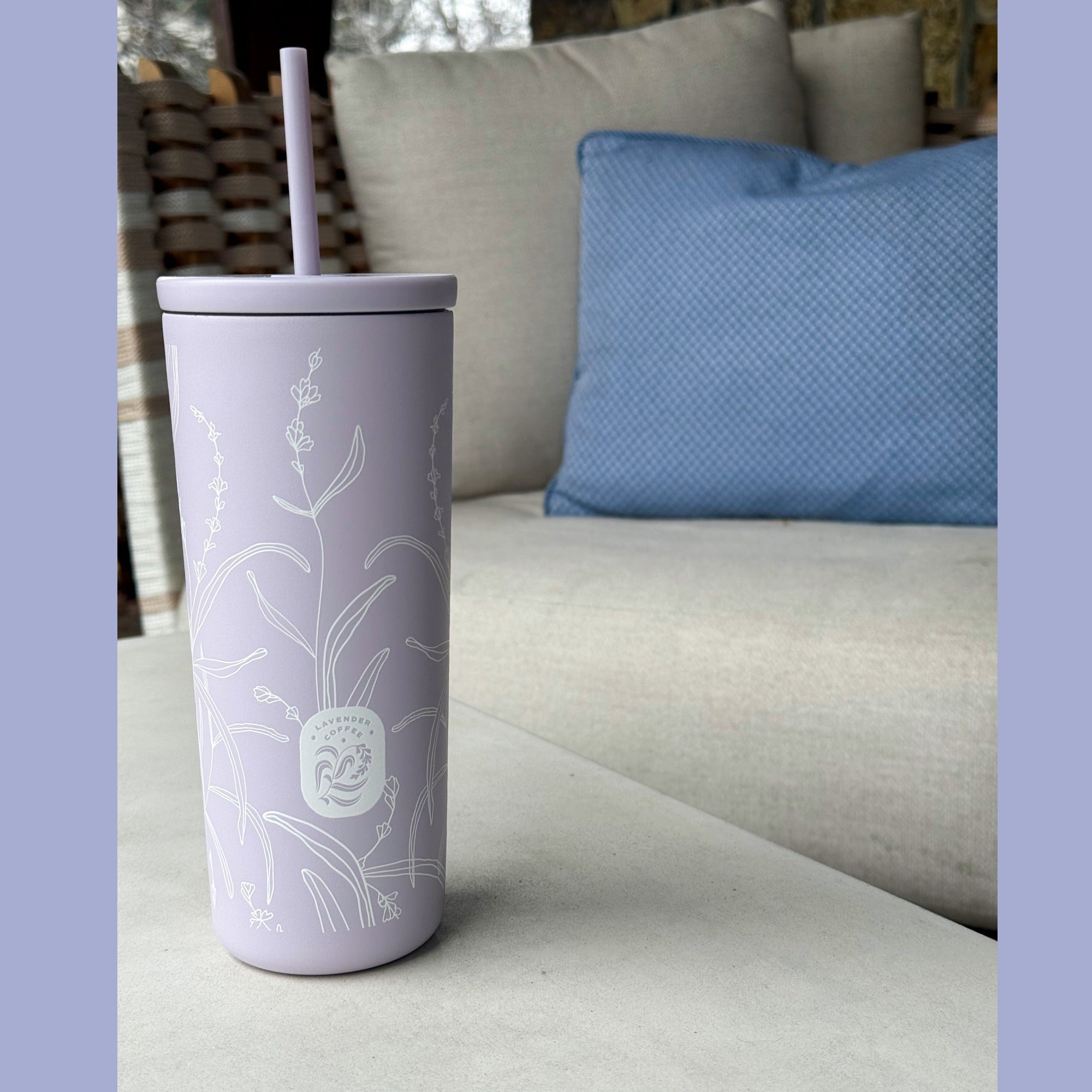Purple tumbler with white floral design on a couch