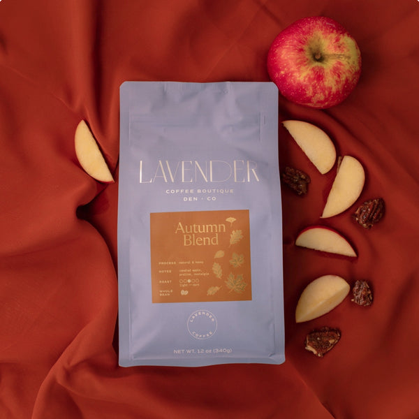 Lavender Autumn Blend coffee package on a red fabric background with apples and nuts.