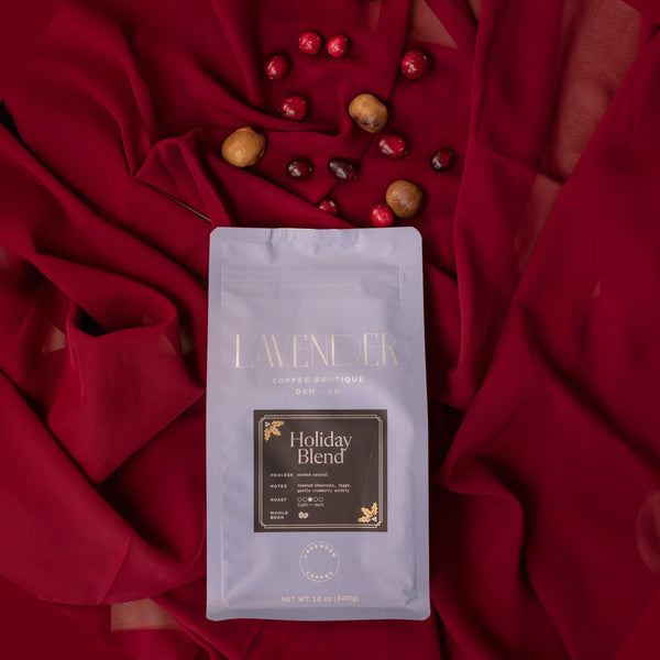 Lavender Holiday Blend coffee package on a red fabric background with berries.