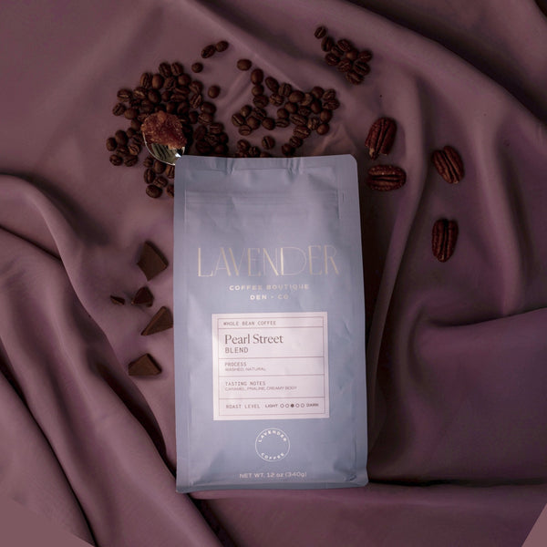 Coffee package labeled 'Lavender' with coffee beans and pecans on a purple fabric background