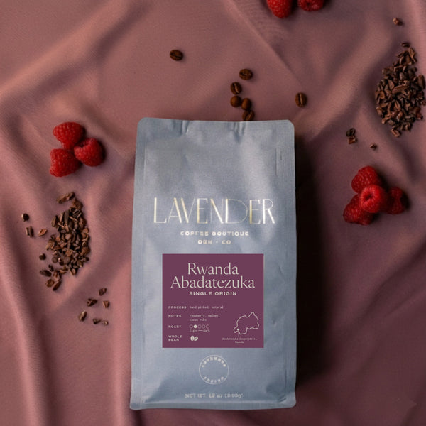 Lavender Coffee Boutique Rwanda Abadatezuka single origin coffee bag with raspberry and cacao nibs on a purple fabric background